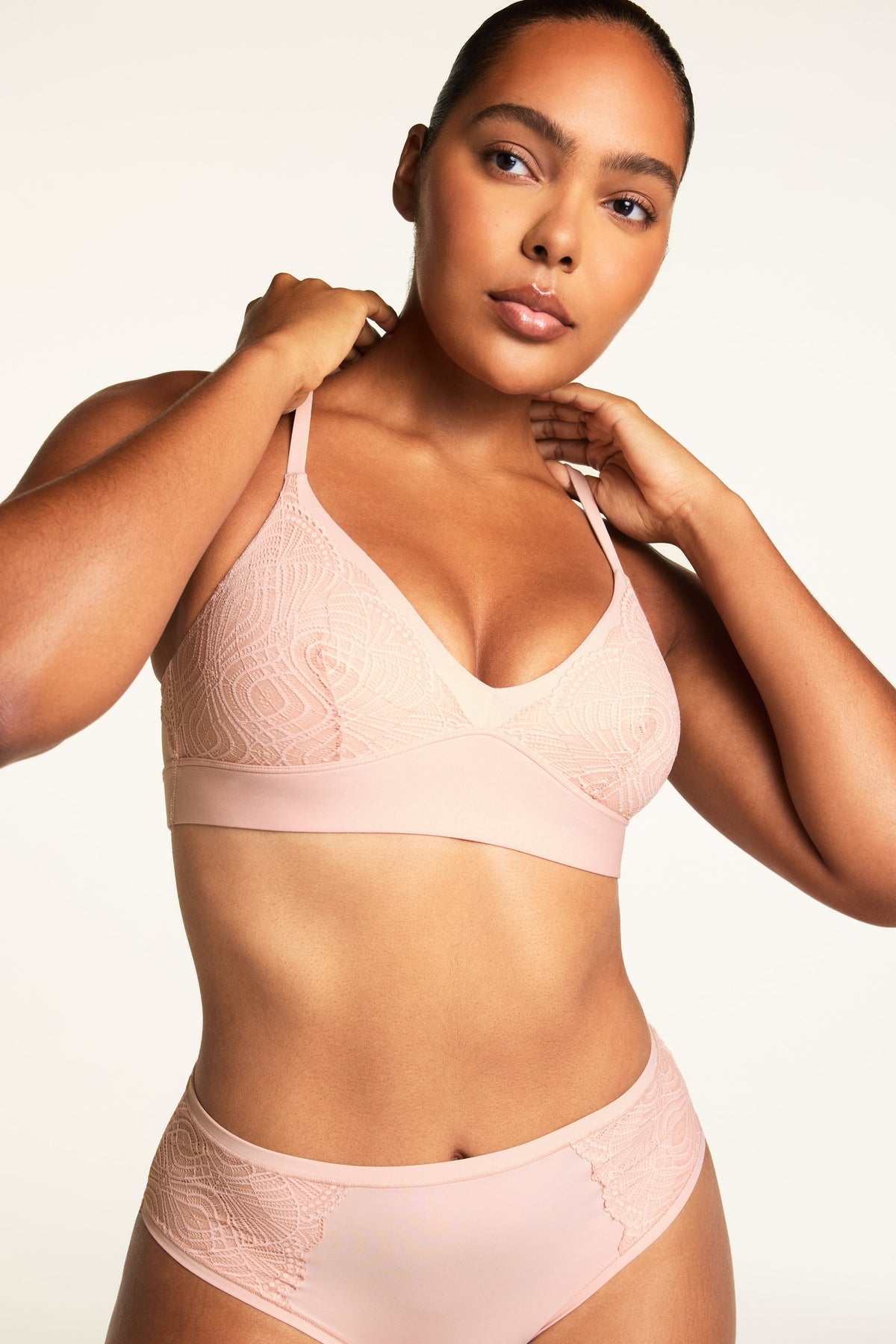 On a warm white studio backdrop, Amber wears the Bliss Lace Bralette in Ember Rose and Bliss Lace Highwaist Brief in Ember Rose, showing the lace-trimmed V-neckline, delicate lace cups, and high-waisted brief with lace detailing.