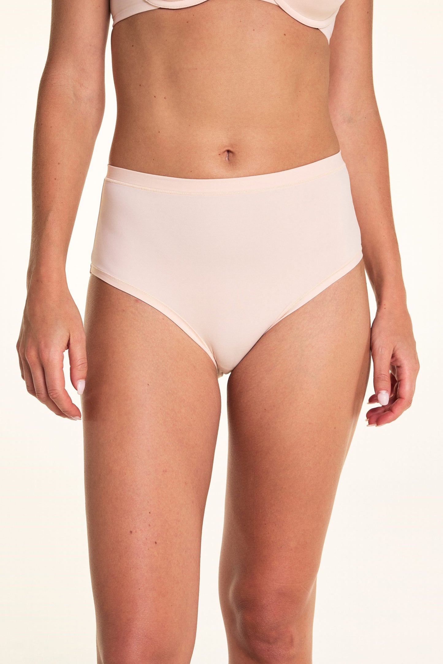 On a white studio backdrop, Alexis wears the Bliss Highwaist underwear in Rose, featuring a smooth high-rise silhouette with full coverage and a soft waistband. sizing: Alexis wears size Small