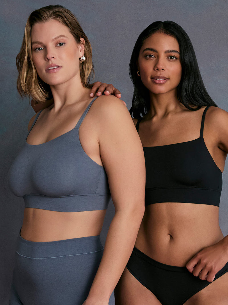 Two models wearing the Cloud Cotton Thin Strap Bralette—one in Slate, the other in Black. The image highlights the minimalist design, ultra-soft cotton fabric, and thin shoulder straps.