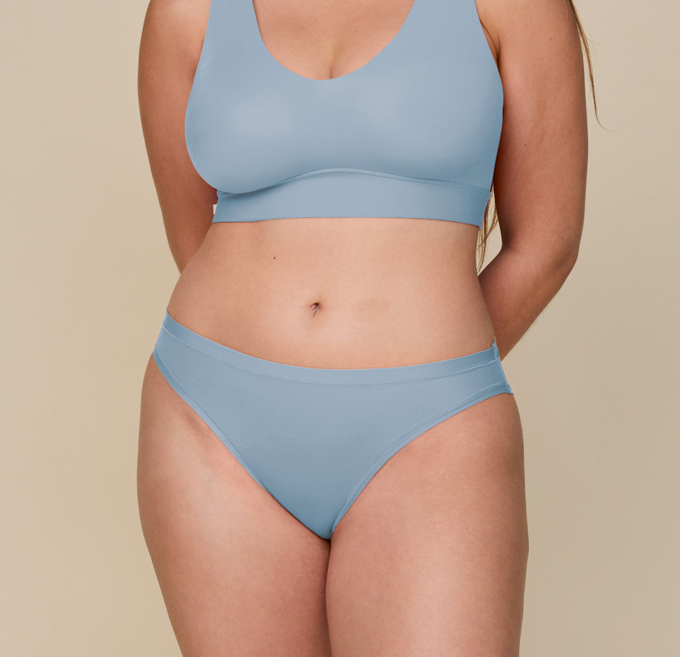 Front view of Summerlyn wearing the Bliss Bikini in Glacier. The mid-rise bikini sits smoothly on the hips with a clean, minimal seam edge. Paired with the matching Bliss Bralette, the soft blue set highlights the stretch and comfort of the fabric. sizing: Summerlyn wears size Large