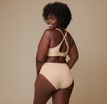 Akesha from a back angle, showing the full coverage of the Bliss Highwaist Brief and the adjustable band of the Bliss Plunge Adjustable Bralette in Beige.