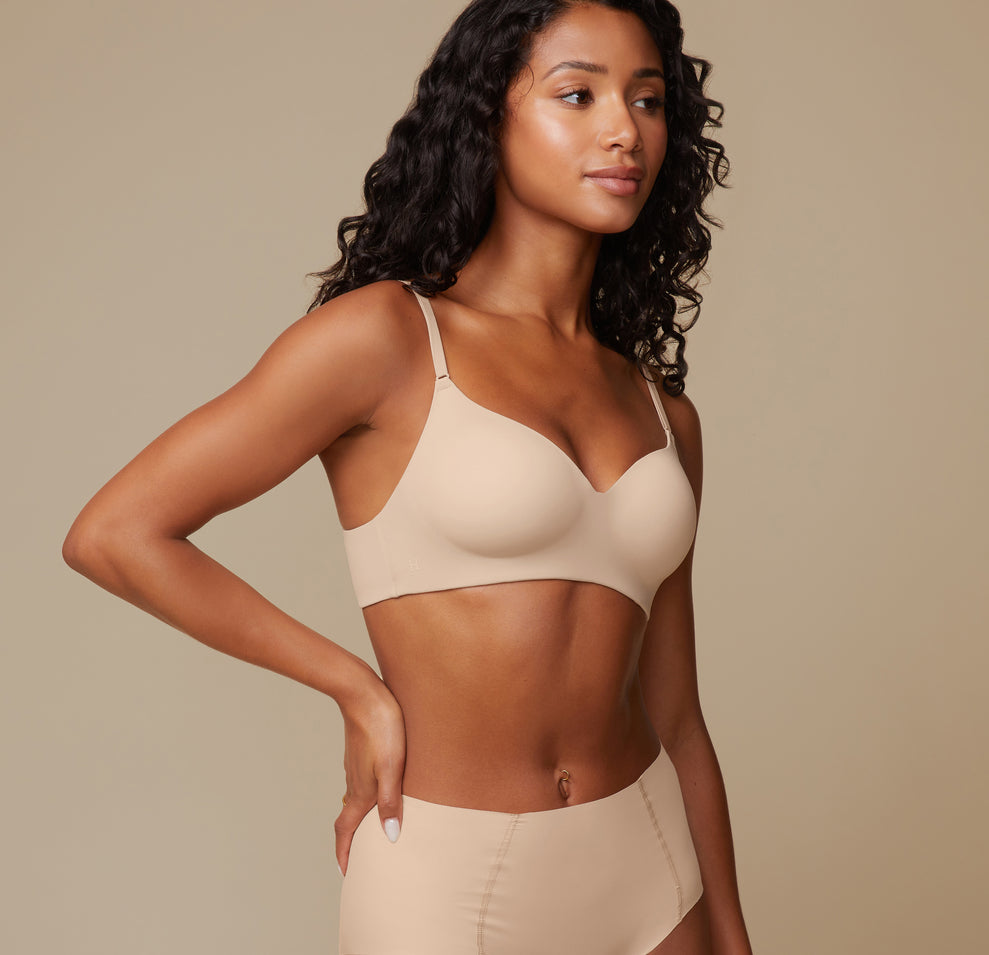 A three quarter view of Ally in the Base Wirefree Bra in Beige, emphasizing the smooth microfiber fabric that is breathable, durable, and soft to the touch.