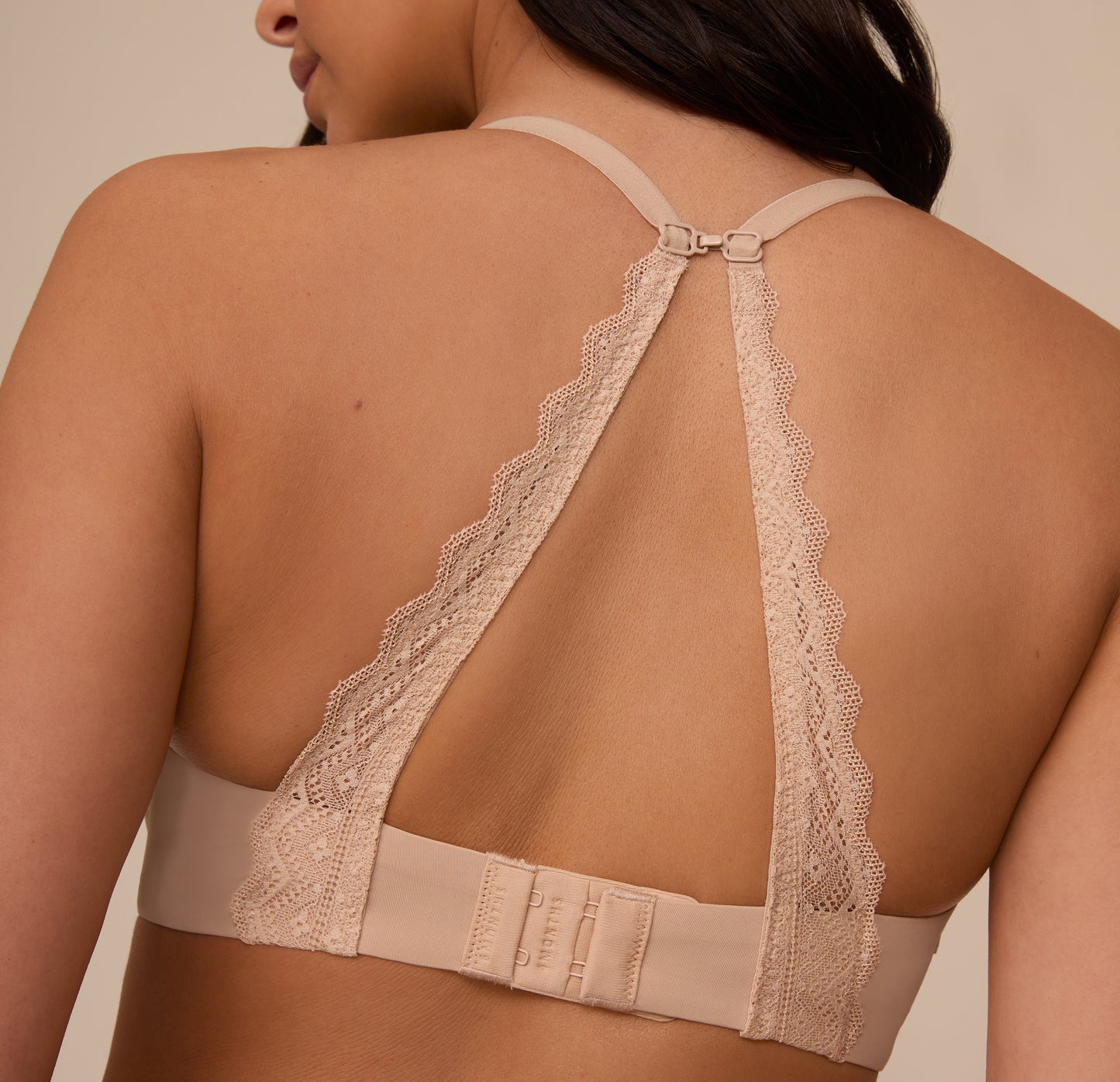 Close-up of Marcela wearing the Base Lace T-Shirt Bra in Beige with the J-hook fastened in a racerback position. The scalloped lace detailing adds elegance while showcasing the bra’s convertible functionality.