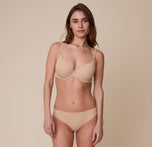 Gracie stands wearing the Base T-Shirt Bra in Beige with the matching No-Show Bikini, displaying the comfortable fit and supportive structure.