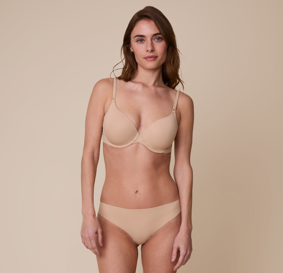 Gracie stands wearing the Base T-Shirt Bra in Beige with the matching No-Show Bikini, displaying the comfortable fit and supportive structure.