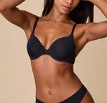 Ally models the Base T-Shirt Bra in Black, displaying a front view of the bra’s smooth design with lightly padded cups and adjustable straps. sizing: Ally wears 32D