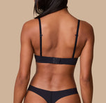 Ally showcases the back of the Base T-Shirt Bra in Black, emphasizing the adjustable hook-and-eye closure and slim, supportive straps.