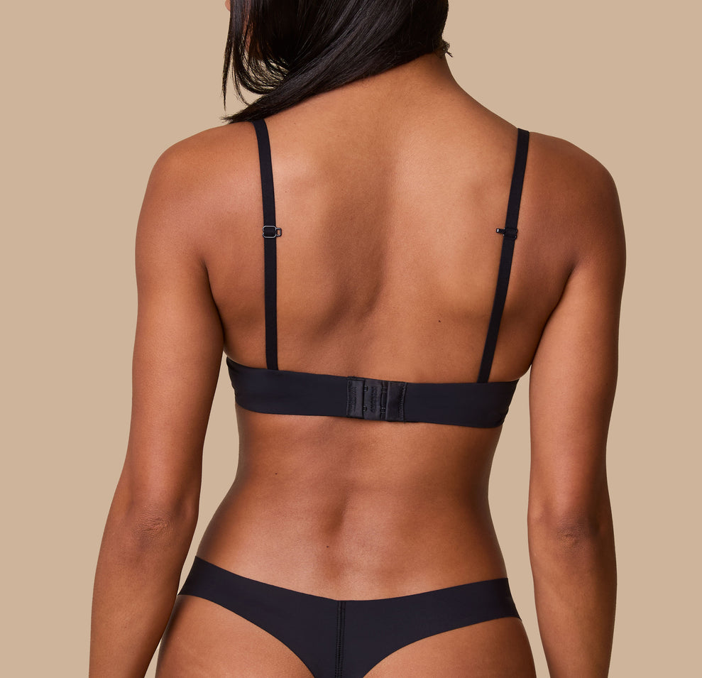 Ally showcases the back of the Base T-Shirt Bra in Black, emphasizing the adjustable hook-and-eye closure and slim, supportive straps.