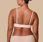 India displays the back of the Base T-Shirt Bra in Rose, highlighting the adjustable hook-and-eye closure and slim, adjustable straps.