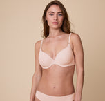 Gracie models the Base T-Shirt Bra in Rose, standing in a relaxed pose to highlight the smooth, form-fitting design. sizing: Gracie wears size 32D