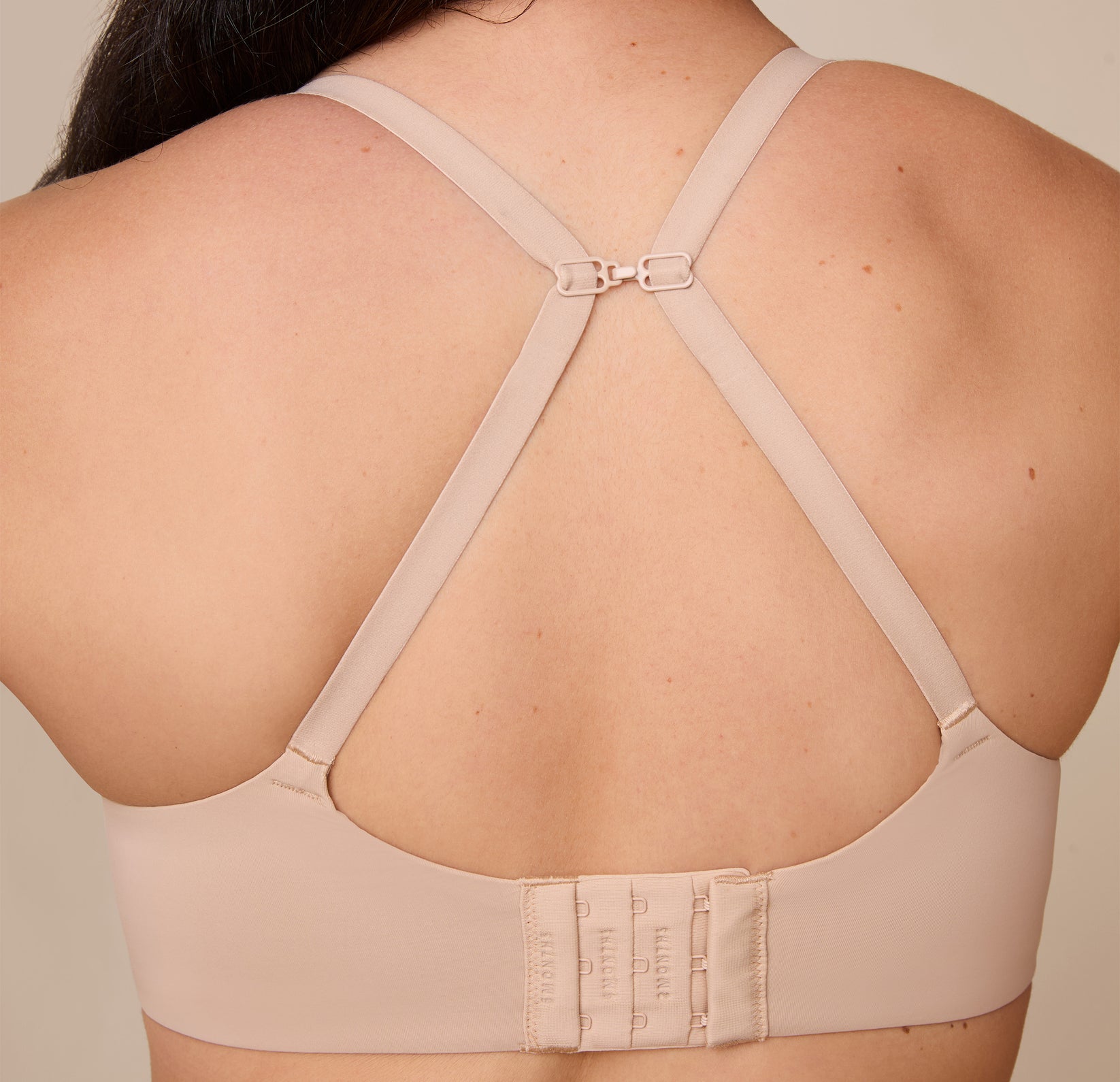 Emersyn showcases the Base Unlined Bra in Beige converted into a racerback using the J-hook, demonstrating the versatile fit and extra lift.