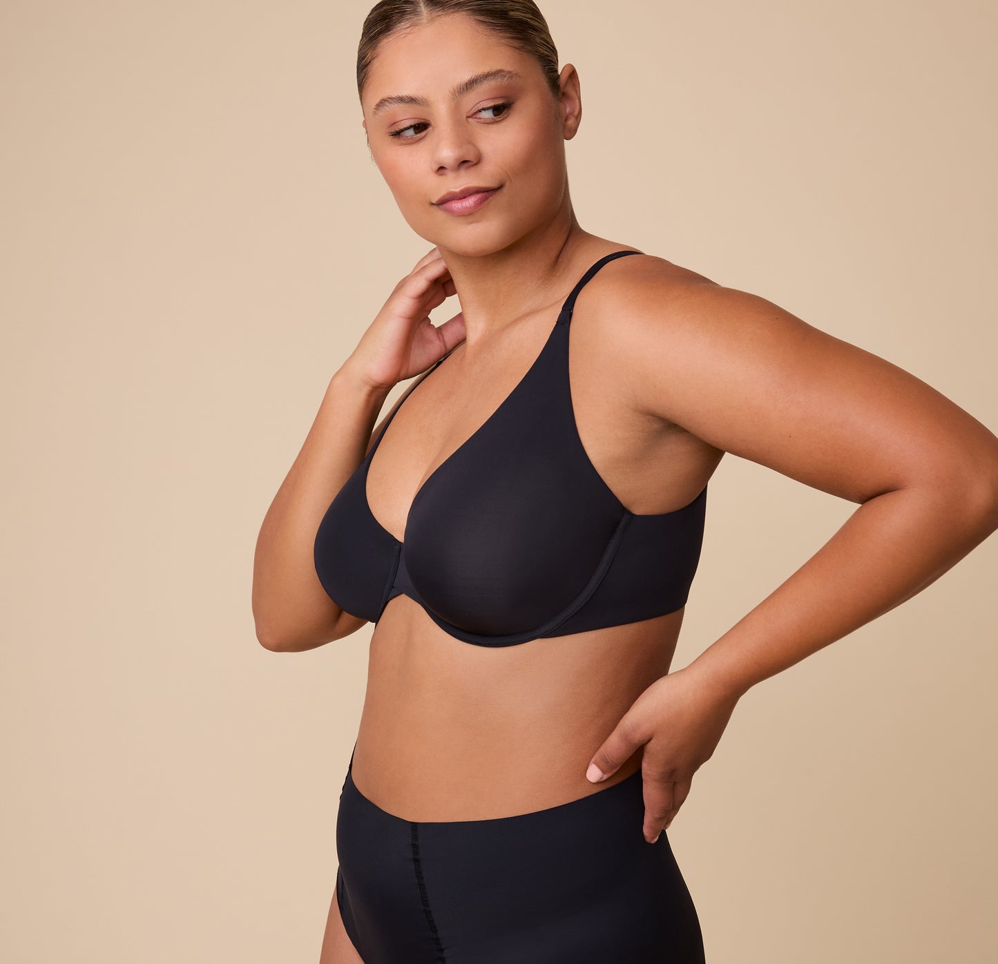 India in a three-quarter side pose, modeling the Base Unlined Bra in Black paired with the matching No-Show Highwaist Brief.