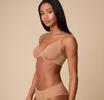 Ally in a side pose, showcasing the smooth, seamless construction of the Base Unlined Bra in Tan for all-day comfort.