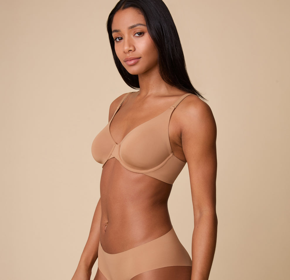 Ally in a side pose, showcasing the smooth, seamless construction of the Base Unlined Bra in Tan for all-day comfort.