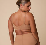 A back view of India wearing the Base Unlined Bra in Tan, featuring the wide back band and fully adjustable straps for an optimal fit.