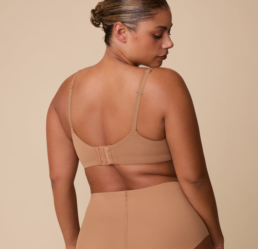 A back view of India wearing the Base Unlined Bra in Tan, featuring the wide back band and fully adjustable straps for an optimal fit.