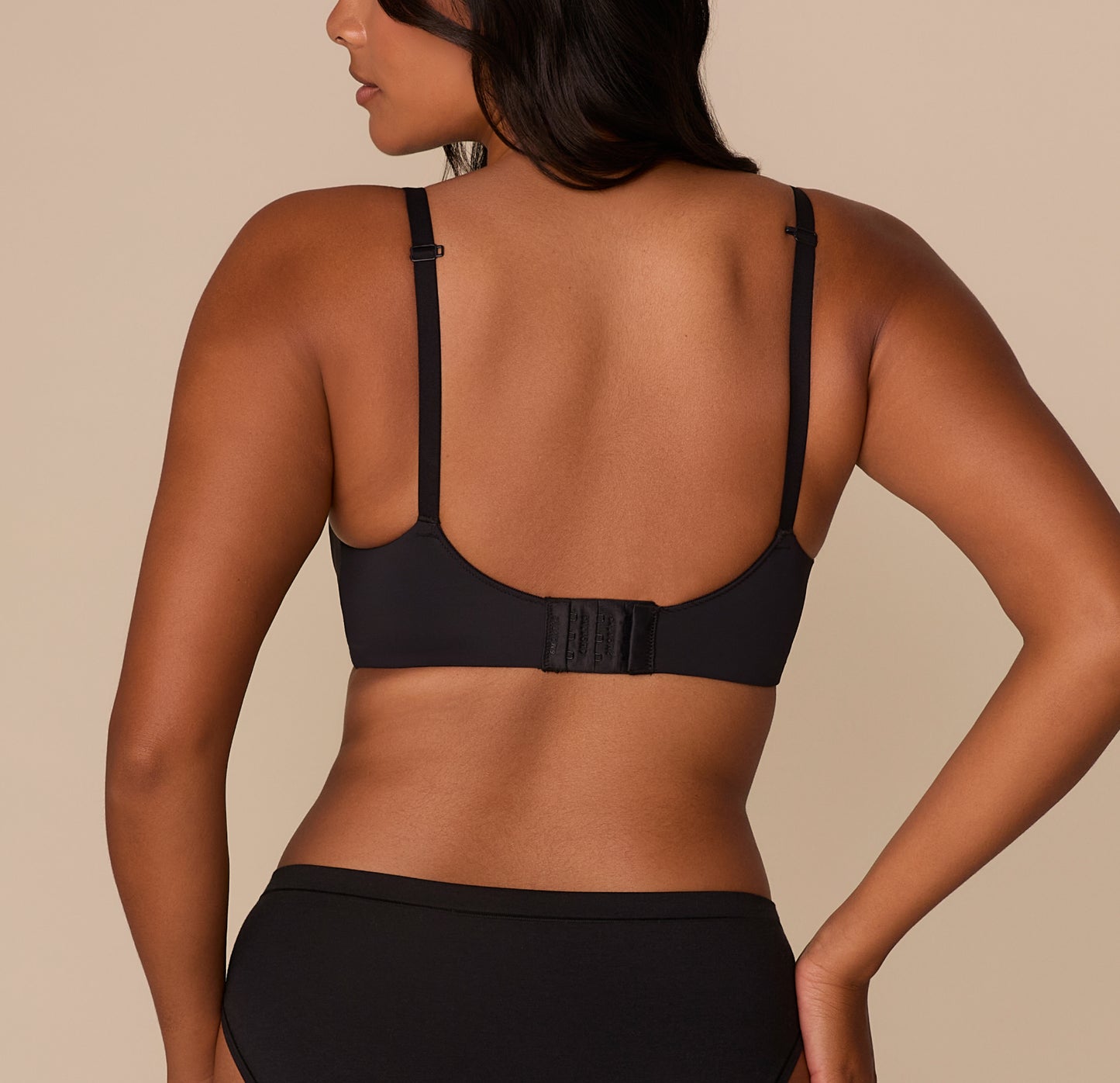 Back view of Victoria wearing the Base Wirefree T-Shirt Bra in Black. The image shows the hook-and-eye closure and adjustable straps designed for everyday support.