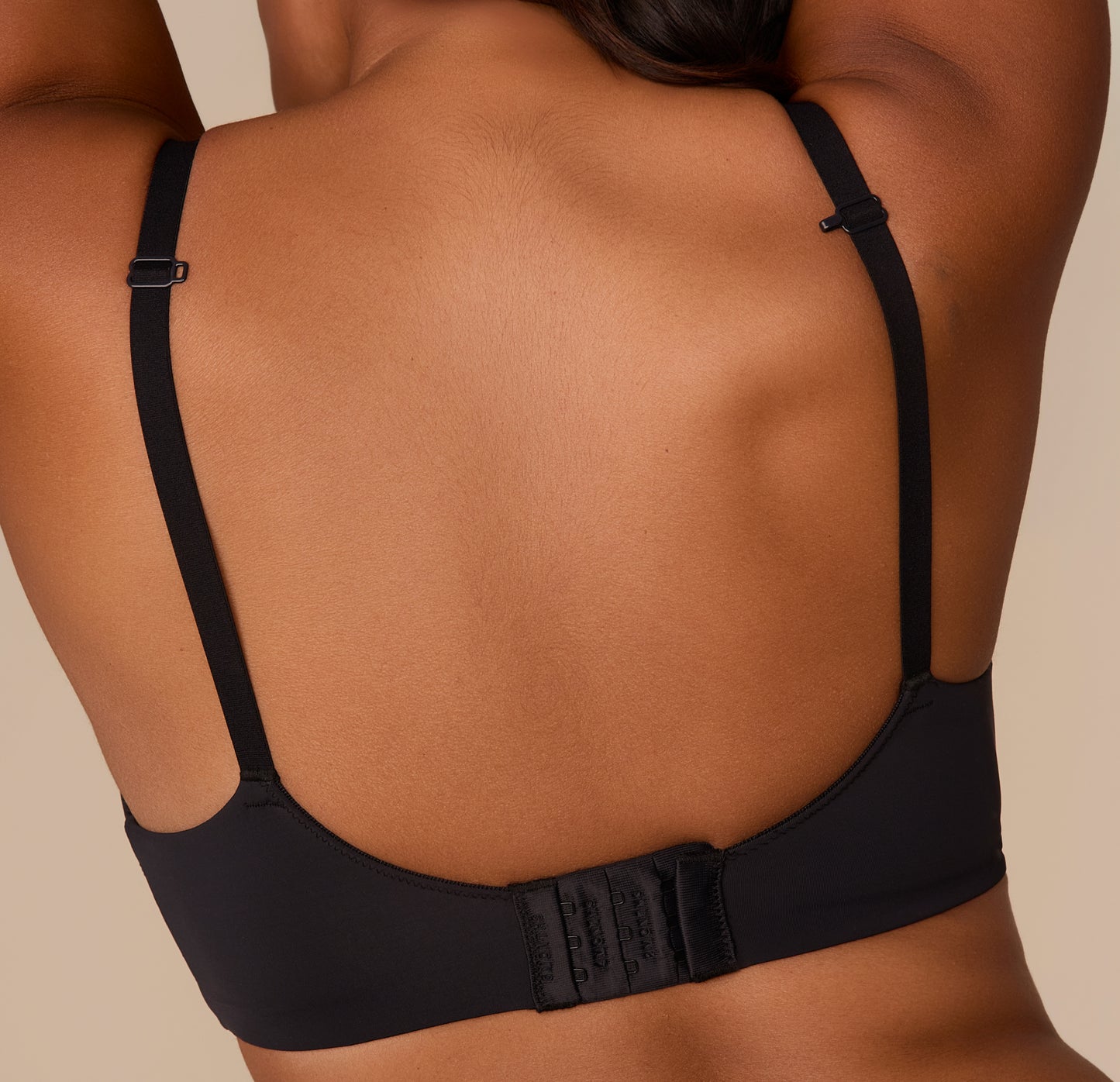 Close-up of the back of Victoria wearing the Base Wirefree T-Shirt Bra in Black. The image emphasizes the smooth back band and three-row hook-and-eye closure.