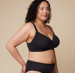 A side view of Bianca in the Base Wirefree Bra in Black, emphasizing the smooth microfiber fabric that’s breathable and soft, paired with the wire-free design for ultimate comfort.
