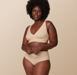 Akesha in the Bliss Plunge Adjustable Bralette and Bliss Highwaist Brief in Beige against a beige background.