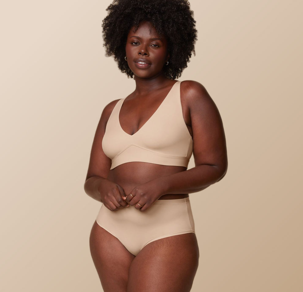 Akesha in the Bliss Plunge Adjustable Bralette and Bliss Highwaist Brief in Beige against a beige background.