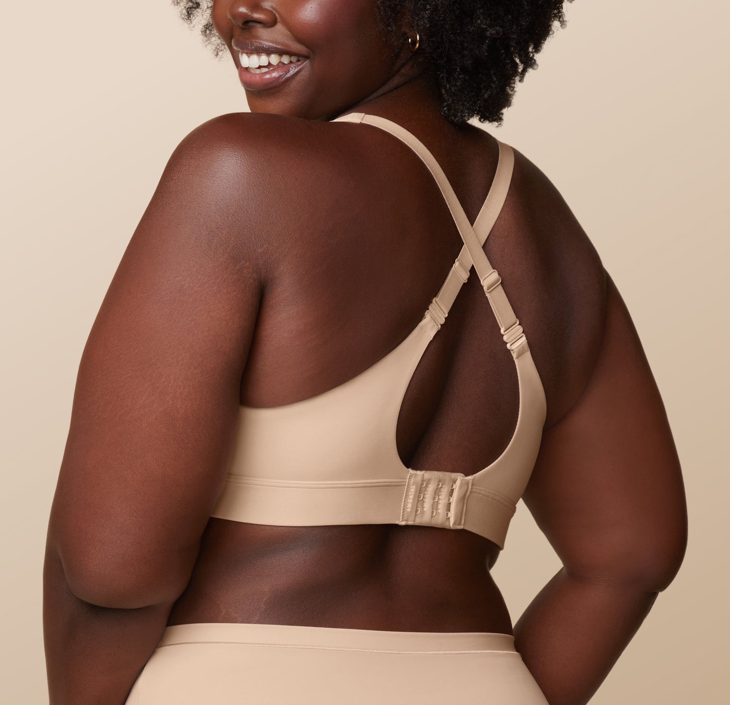Akesha from a back angle, showing the full coverage of the Bliss Highwaist Brief and the racerback configuration of the Bliss Plunge Adjustable Bralette in Beige.