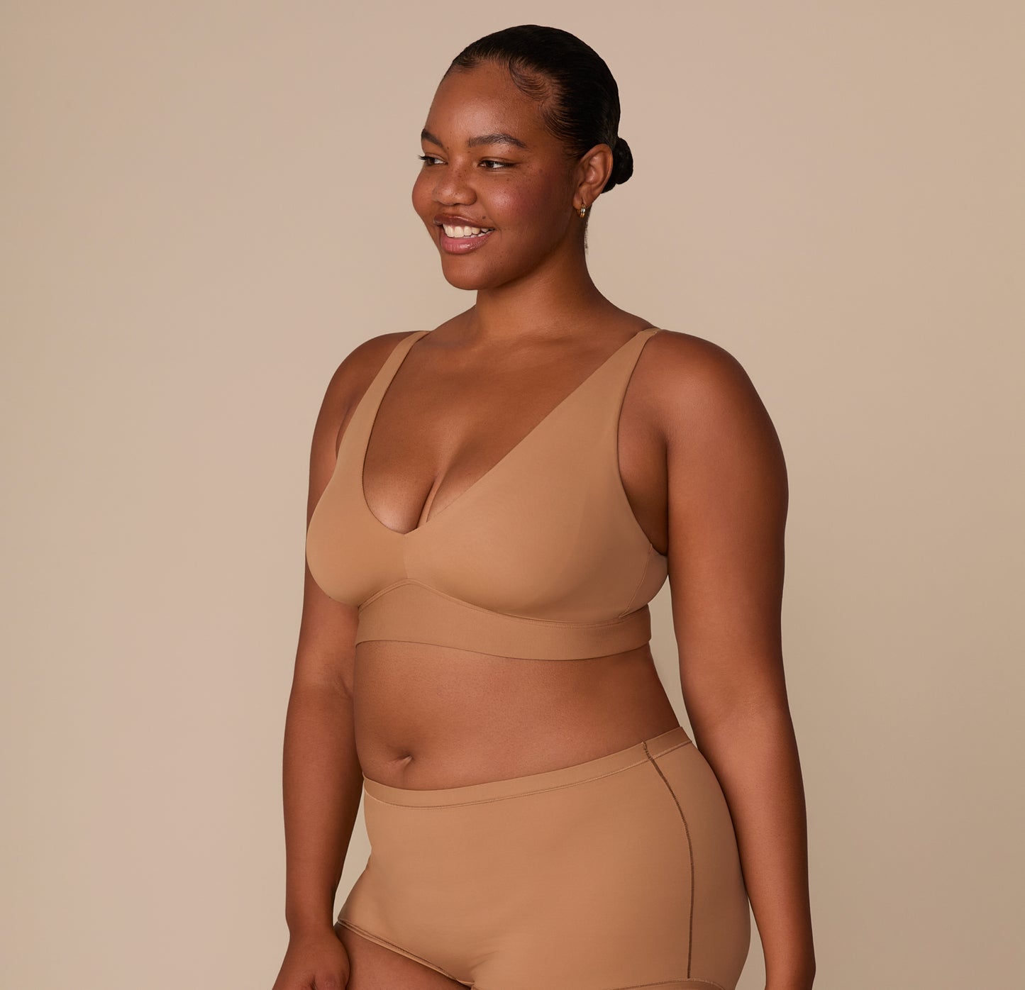 Three-quarter view of Zarria in the Tan Bliss Bralette, showcasing the plunging neckline and smooth fit along the bust.