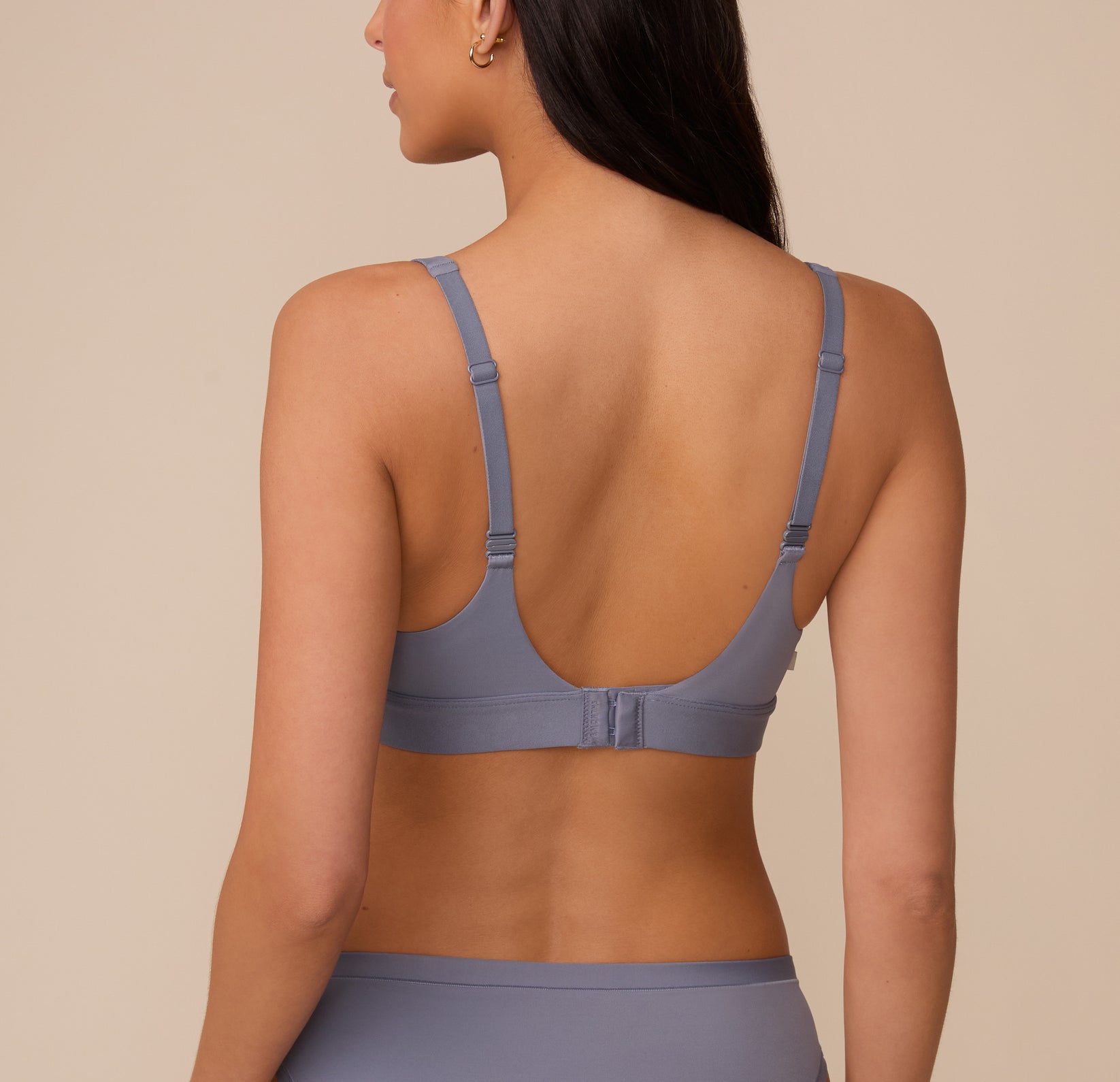 Back view of Marcela wearing the Bliss Plunge Adjustable Bralette in Steel. The image shows the low scoop back, adjustable straps, and hook-and-eye closure for a customizable fit.