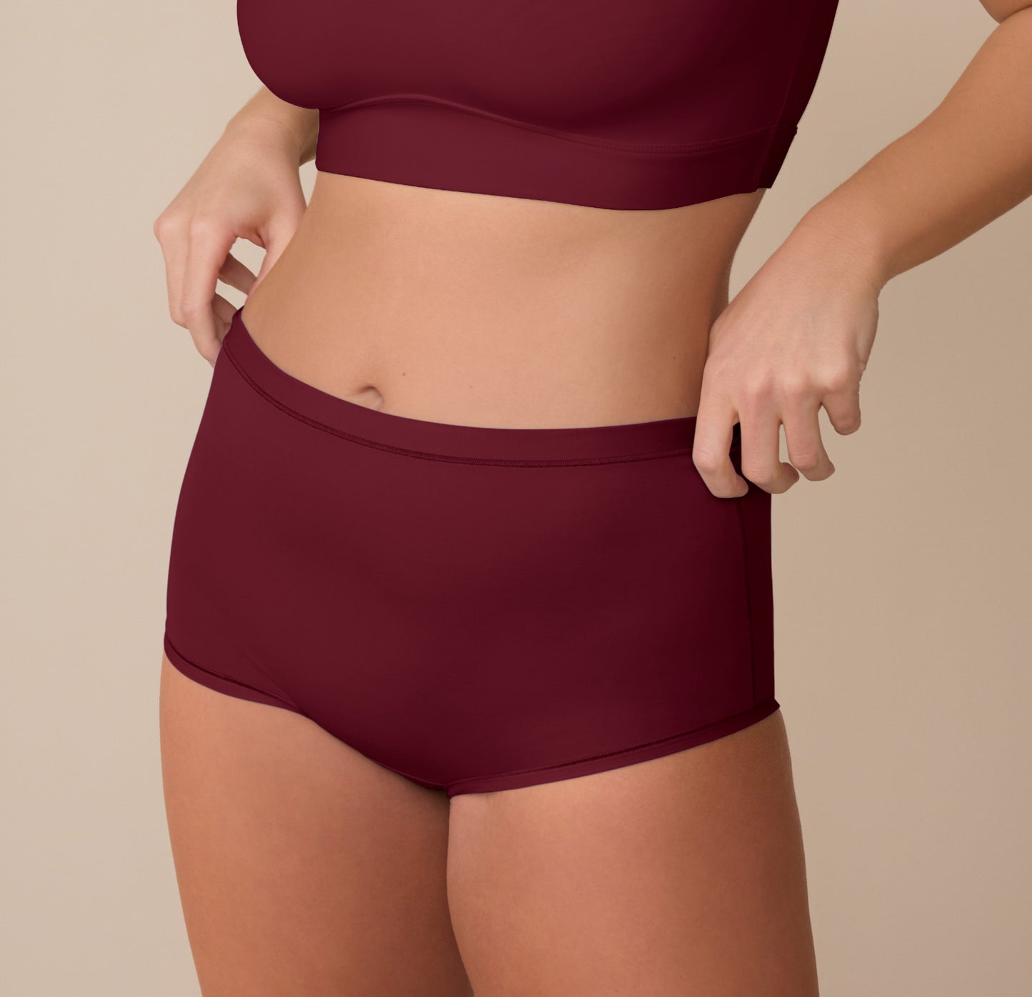 Sonnie adjusting the waistband of the Bliss Boyshort in Bordeaux, showcasing the soft stretch and secure fit.