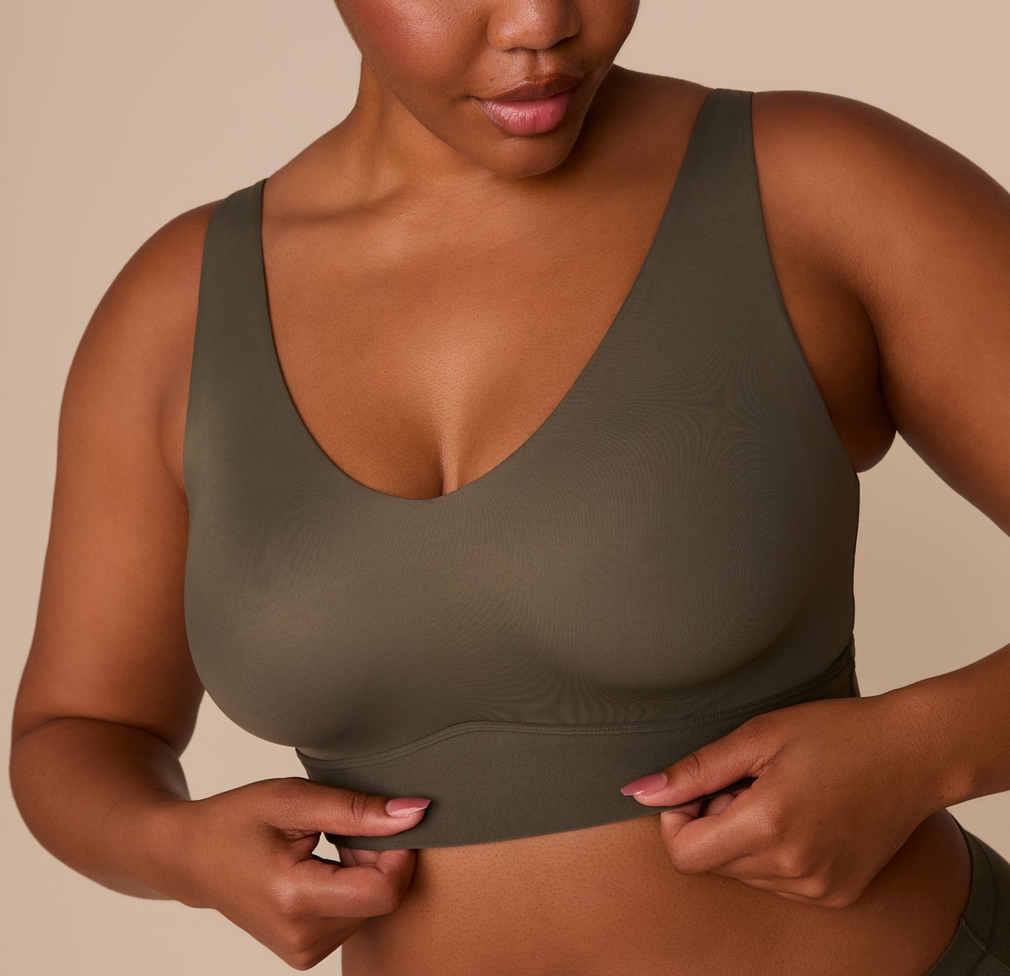 Close-up of Zarria adjusting the Bliss Bralette in Olive, focusing on the soft, stretchy underband and smooth fabric texture.