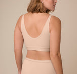 Back view of Victoria wearing the Bliss Bralette in Beige. The scoop back and flexible band hug her shape without digging in.