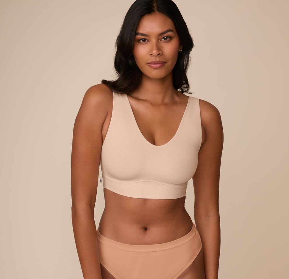 Front view of Victoria wearing the Bliss Bralette in Beige. The deep V neckline and wide straps provide a flattering fit and soft support. sizing: Victoria wears size Medium