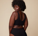 Back view of Akesha wearing the Bliss Bralette in Black. The scoop back reveals the bralette’s sleek silhouette and non-restrictive design.