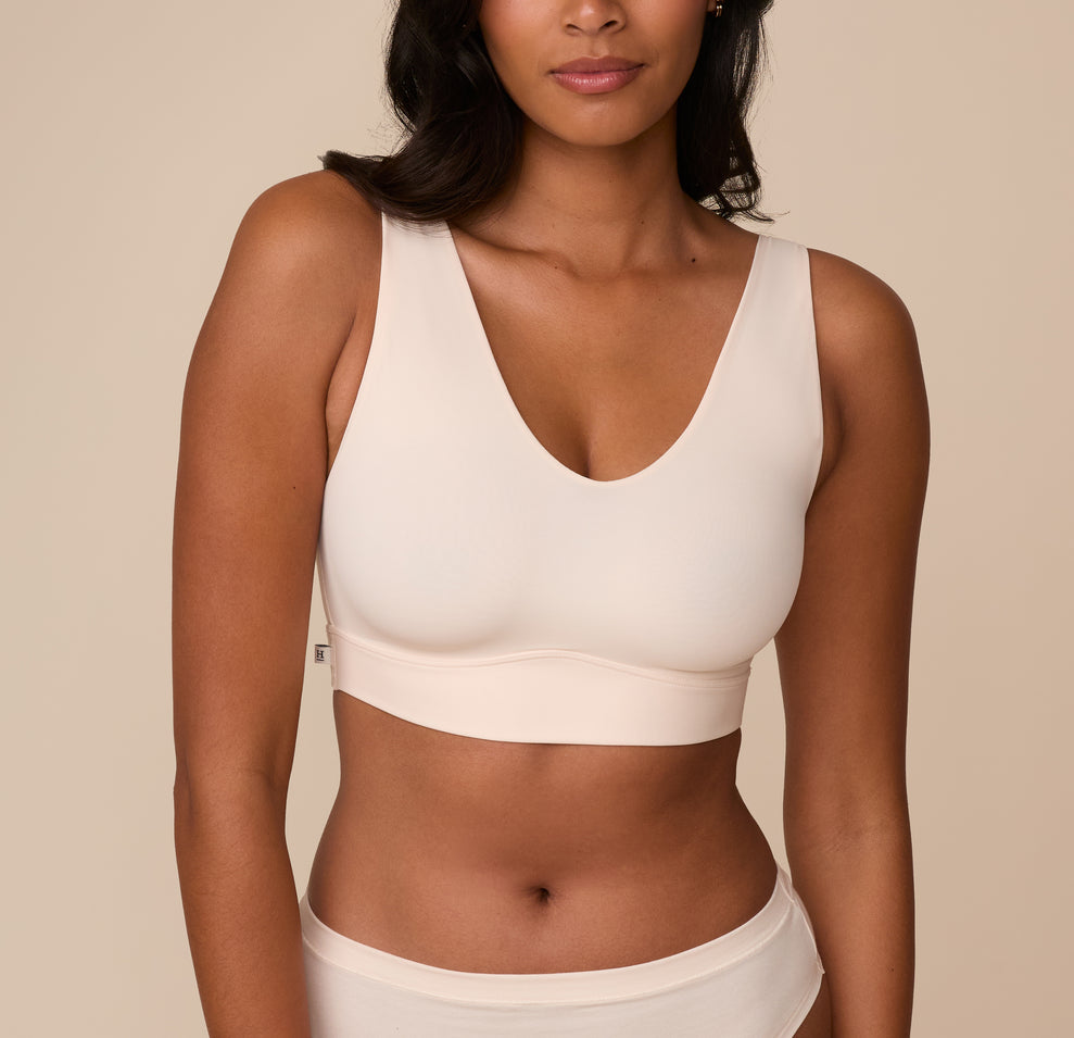 Front view of Victoria wearing the Bliss Bralette in Quartz. Victoria models the Bliss Bralette in Quartz, featuring a moderately low V-neckline and wide shoulder straps. The minimal seam cups offer gentle lift and all-day comfort. sizing: Victoria wears size Medium
