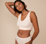 Three quarter angle of Victoria wearing the Bliss Bralette in Quartz. Victoria poses in the Bliss Bralette, showcasing the contoured shape and wide, supportive underband that hugs the body without digging in.