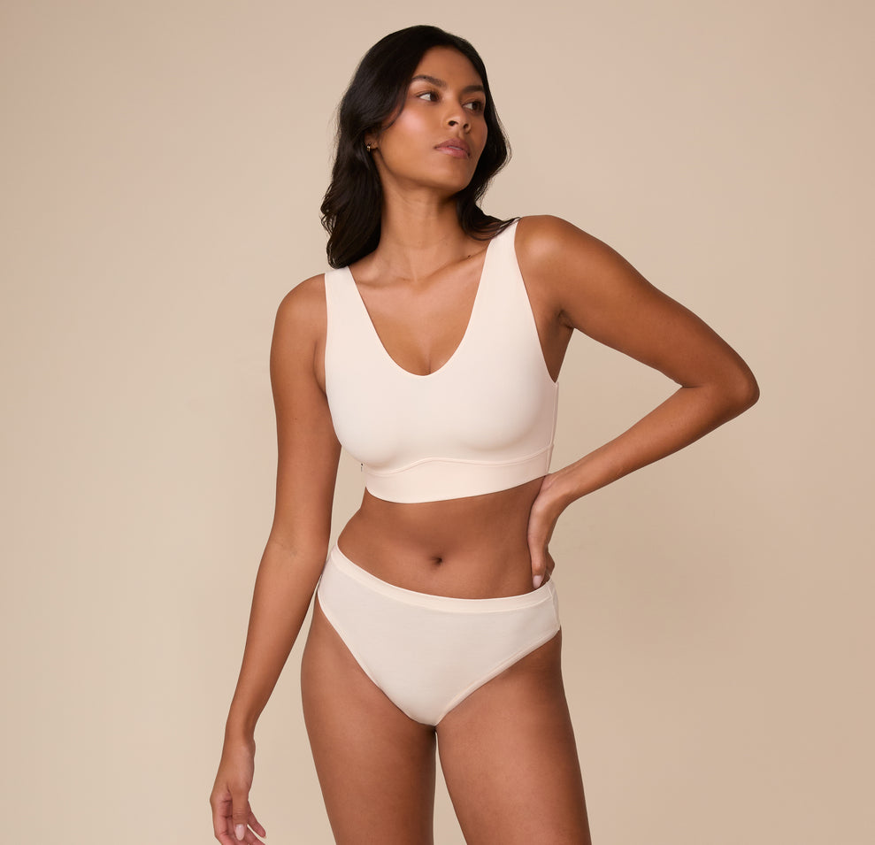 Full-body view of Victoria wearing the Bliss Bralette and the Cloud Cotton Thong in Quartz. Victoria wears the Bliss Bralette and coordinating bottoms in Quartz. The look emphasizes effortless comfort and clean lines designed for real bodies.