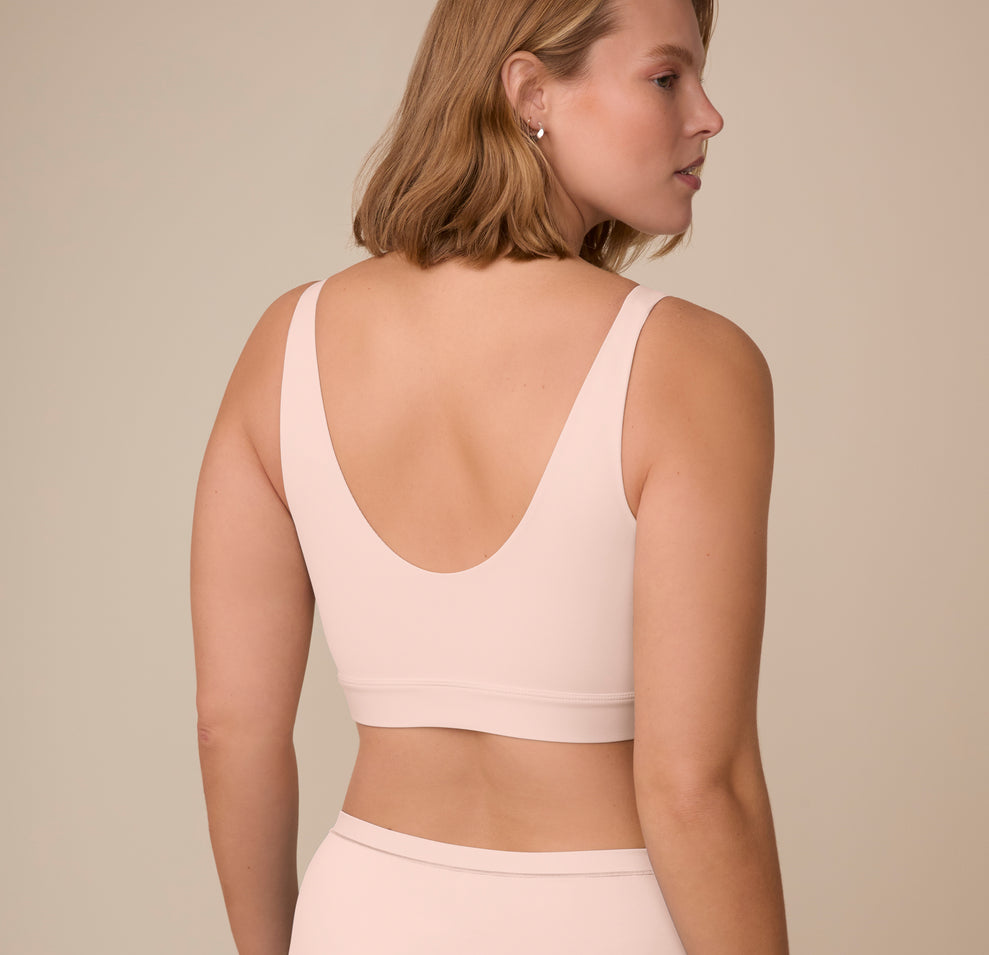 Back view of Sonnie wearing the Bliss Bralette in Rose. The wide, scoop back and soft band sit gently on the skin for a barely-there feel.
