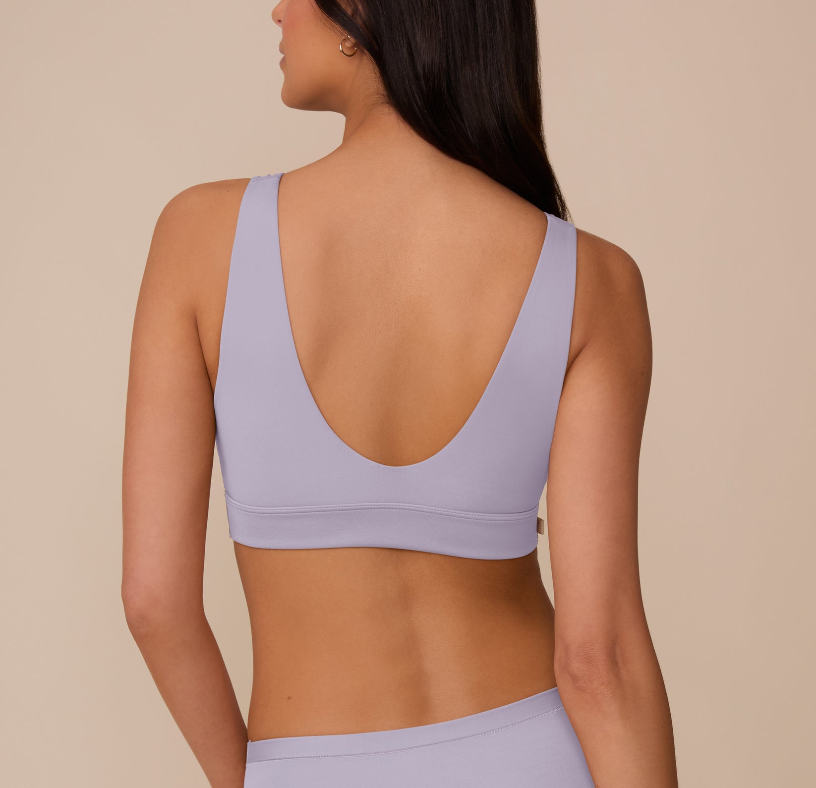 Back view of Marcela in the Bliss Bralette in Violet and Bliss Hiphugger in Violet. The bralette has a wide scoop back and thick straps that offer gentle support, while the hiphugger provides smooth rear coverage.
