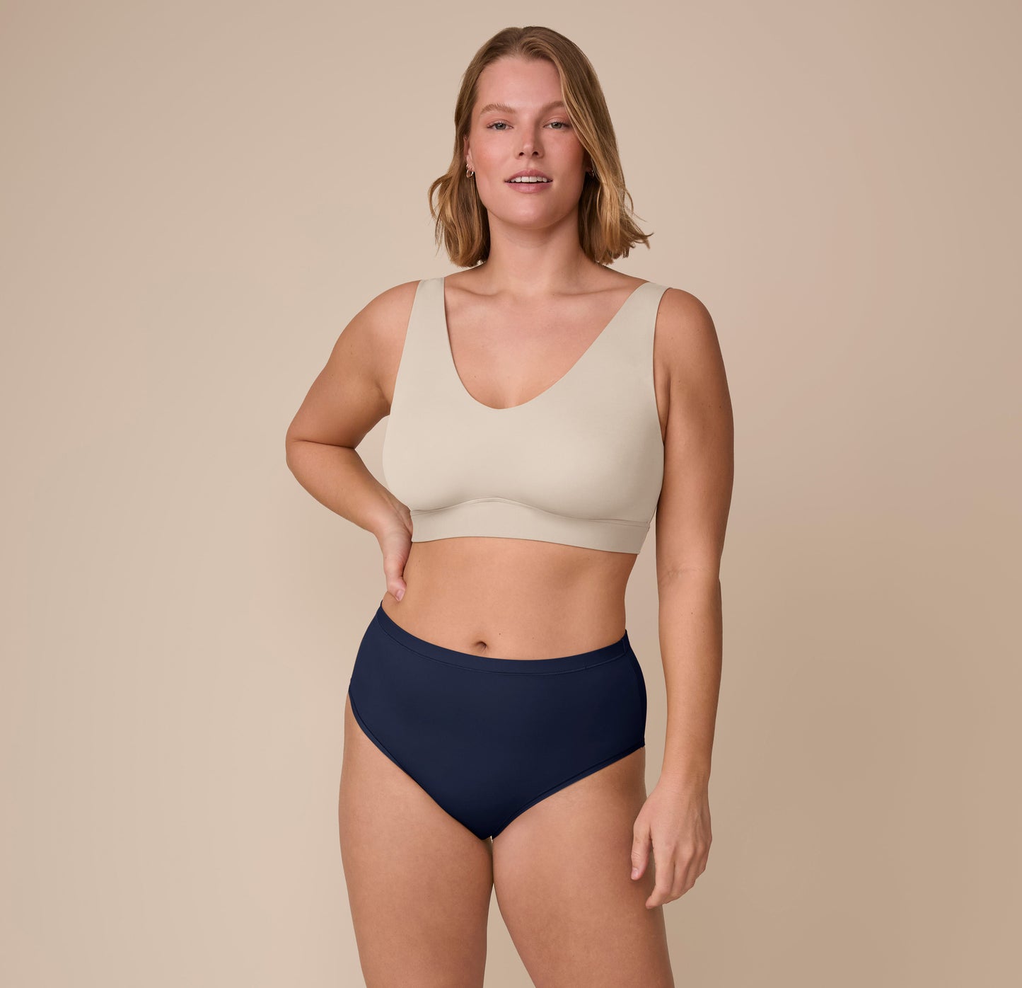 Full-body image of Sonnie modeling the Bliss Highwaist Brief with the Bliss Bralette in Sand, showing a coordinated look with a barely-there feel.