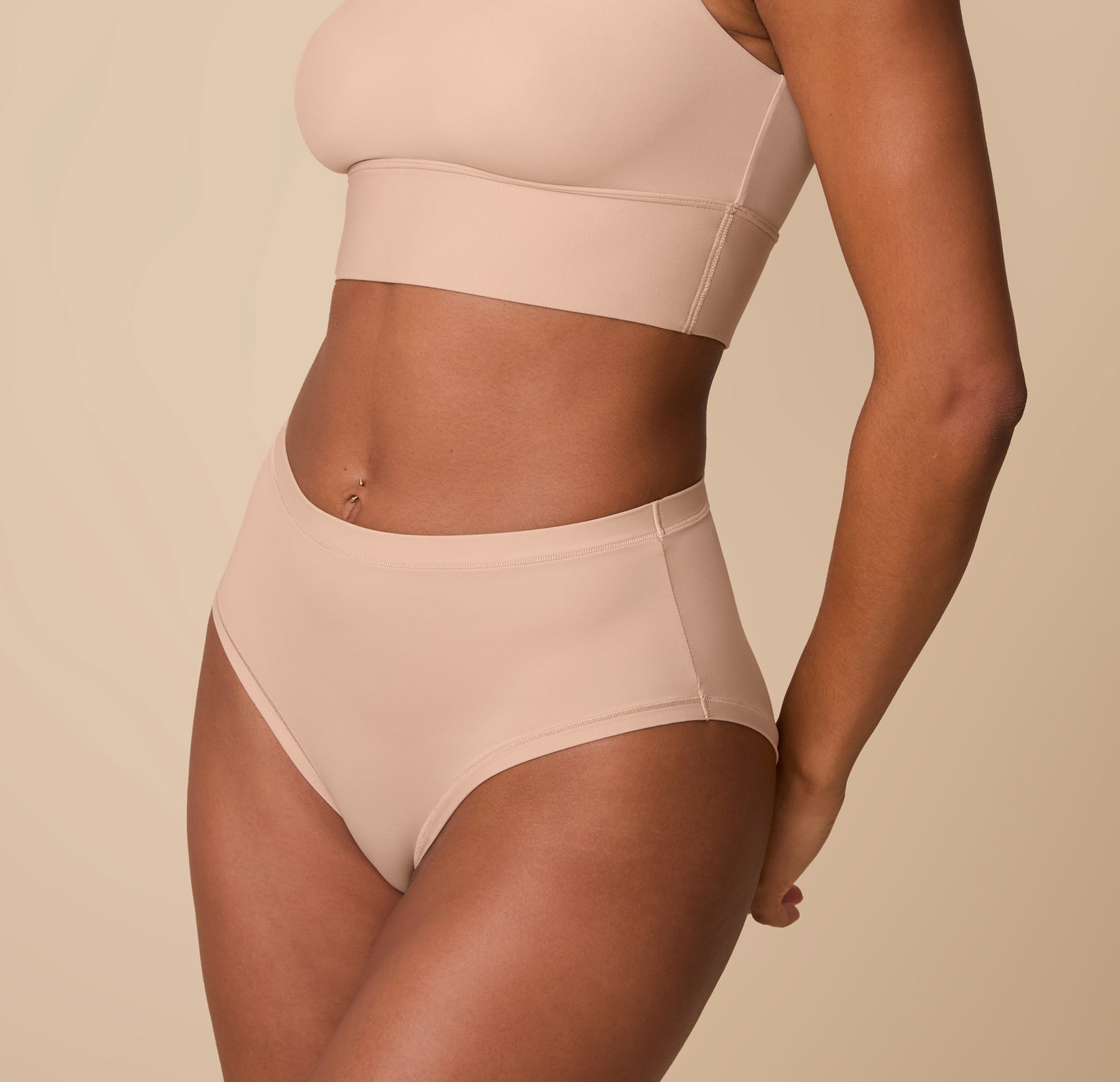Ally wearing the Bliss Highwaist Brief in Beige, captured from a slight angle to highlight the curve-hugging fit and soft, stretchy fabric.