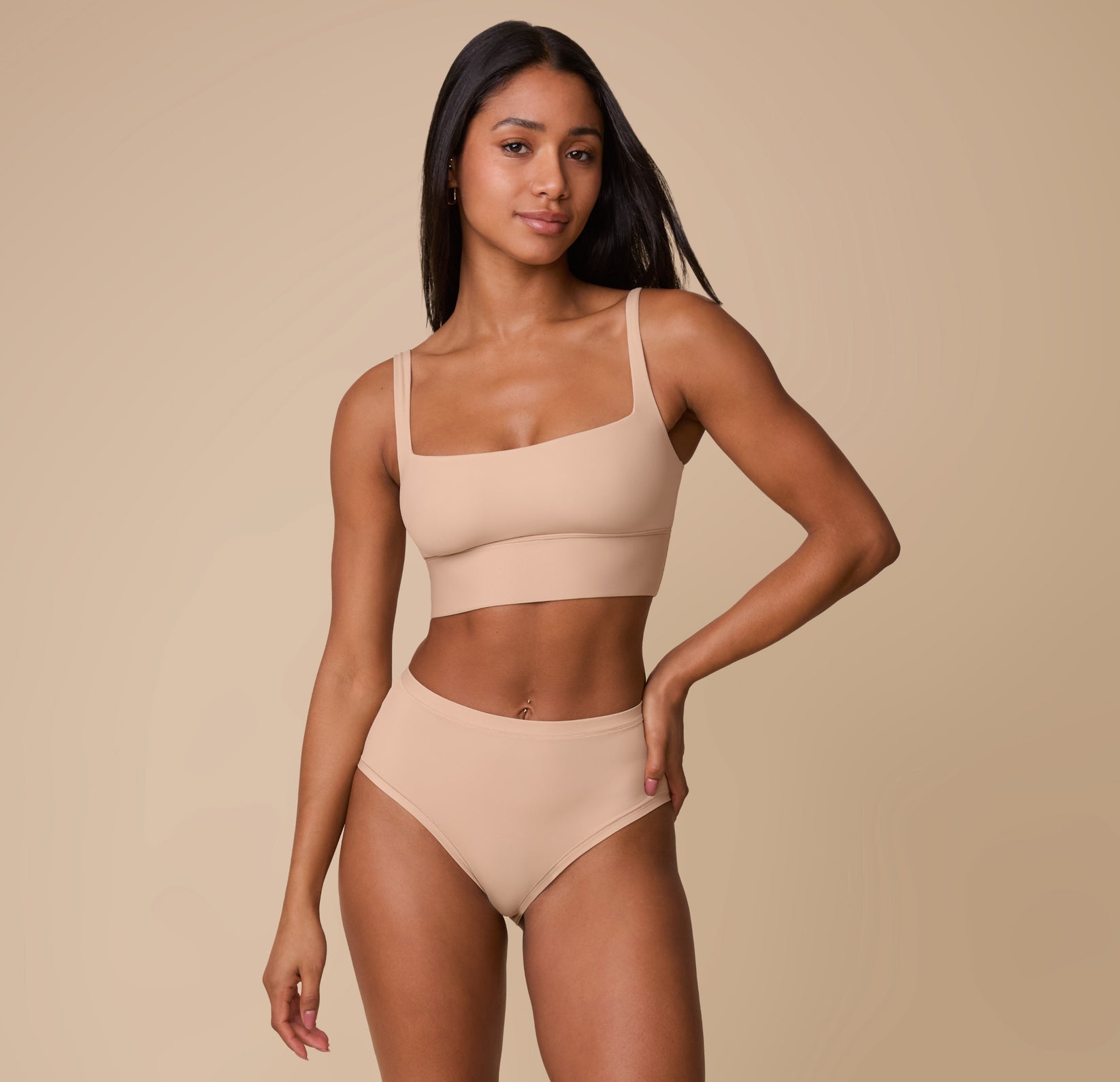 Ally wearing the Bliss Highwaist Brief in Beige, paired with the matching Bliss Square Neck Bralette. She stands confidently, showcasing the sleek and modern design of the brief.