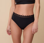 Front view of Gracie wearing the Bliss Lace Highwaist Brief in Black. The soft, stretchy fabric and delicate lace waistband offer a high-rise fit for all-day comfort. sizing: Gracie wears size Small