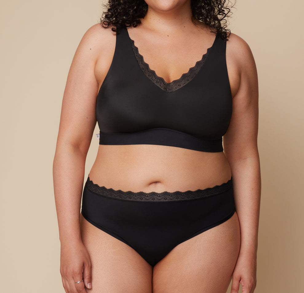 Front view of Bianca in the Bliss Lace Highwaist Brief in Black, featuring a soft, high-rise fit with a delicate lace waistband for a stylish yet comfortable feel. sizing: Bianca wears size XL