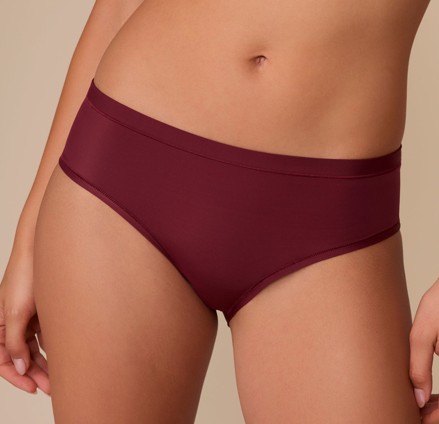 Close-up of the Bliss Hiphugger in Bordeaux on Alexis, emphasizing the smooth waistband, flat seams, and modern silhouette.