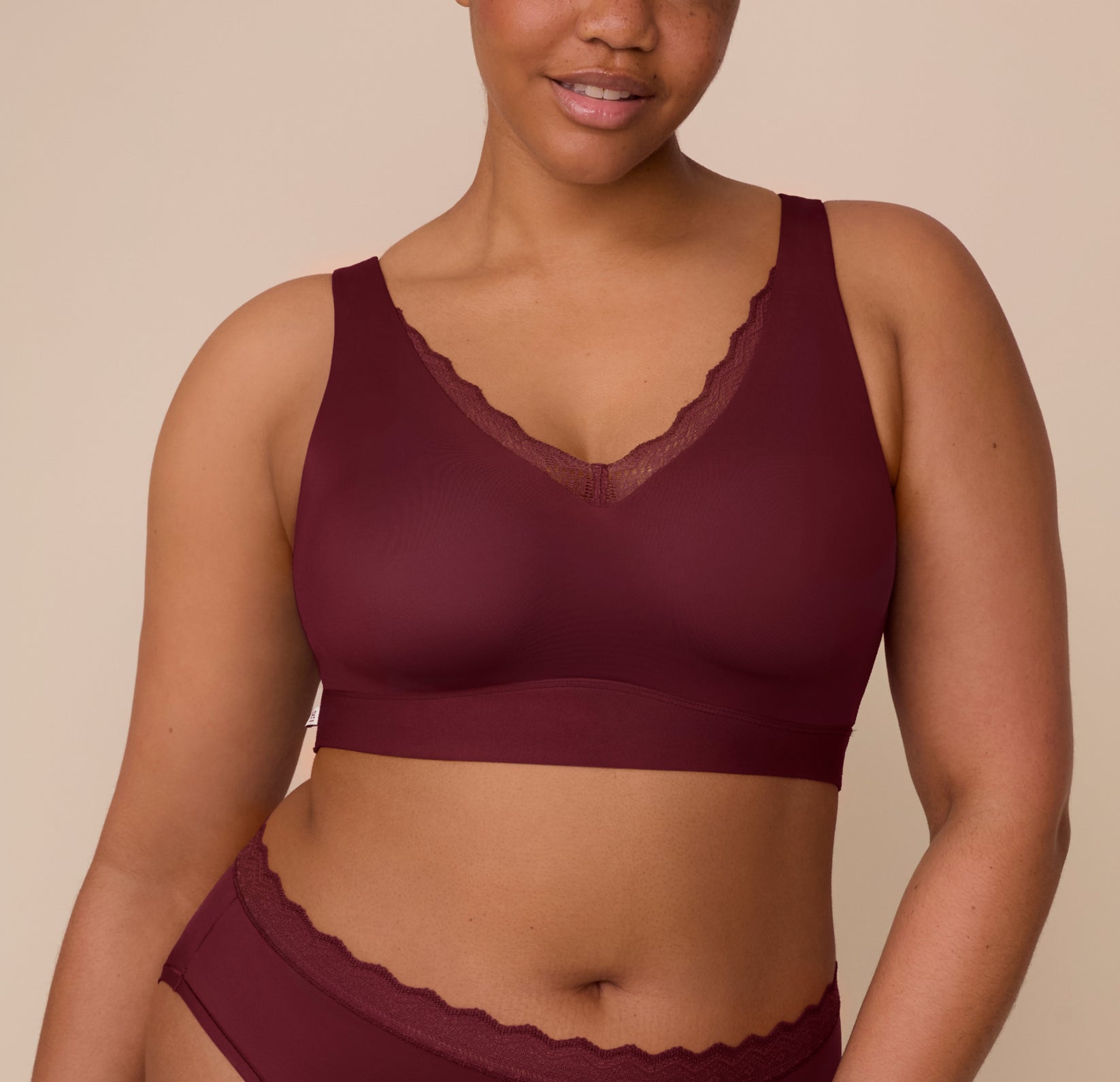 Close-up of Zarria wearing the Bliss Lace Bralette in Bordeaux, showcasing the plunging V-neckline trimmed with scalloped lace and lightly molded cups. sizing: Zarria wears size XL