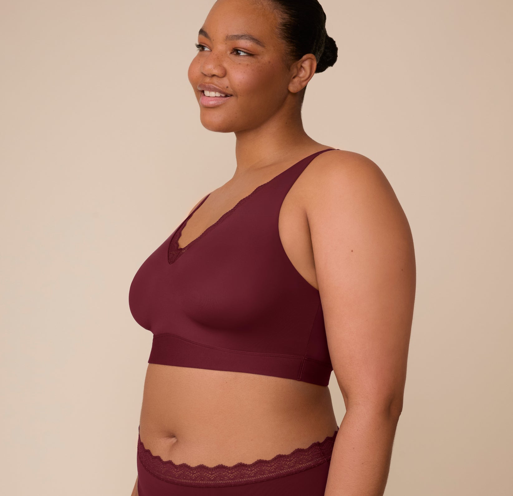 Side angle of Zarria in the Bliss Lace Bralette in Bordeaux, highlighting the wide straps and extended underband for added comfort.