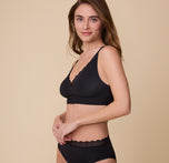 Gracie stands in a relaxed pose, wearing the Bliss Lace Bralette in Black. The image highlights the bralette’s lightweight fabric and comfortable, minimal design.