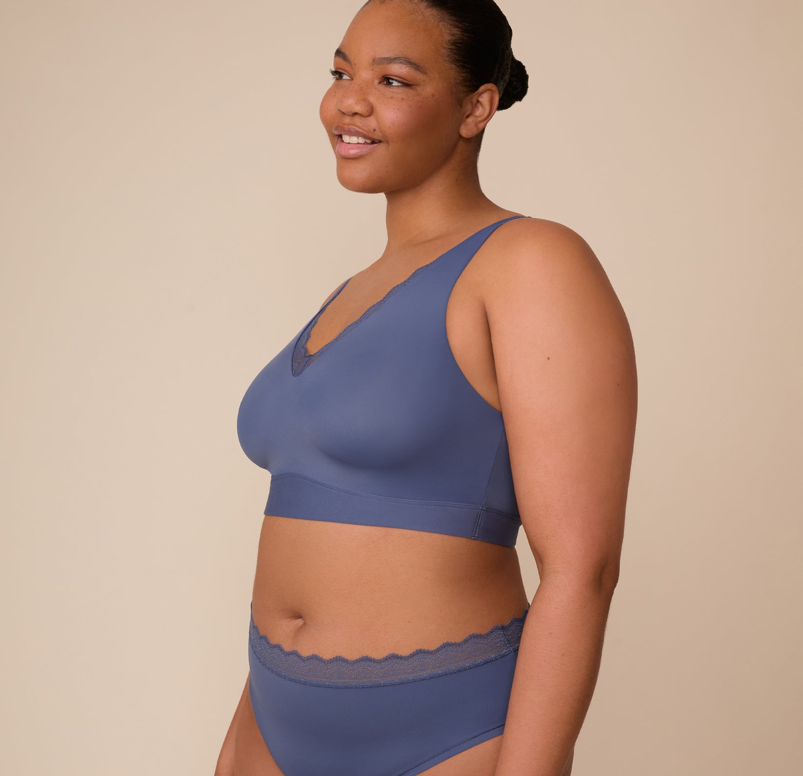 Three quarter profile of Zarria wearing the Bliss Lace Bralette in Twilight. This angle highlights the lightly lined cups and wide straps, designed to provide all-day support without digging in.