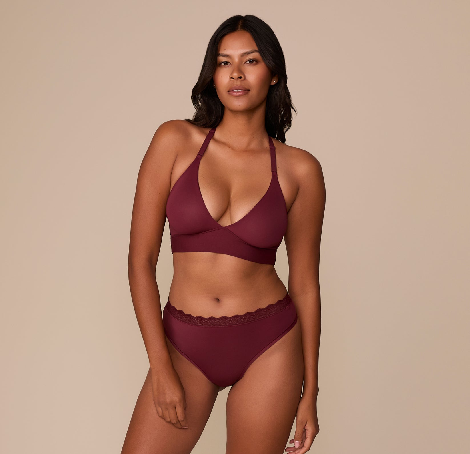 Victoria models the Bliss Lace Halterneck Bralette and matching Bliss Lace Highwaist Thong in Bordeaux. The coordinated set combines ultra-soft fabric and scalloped lace details.