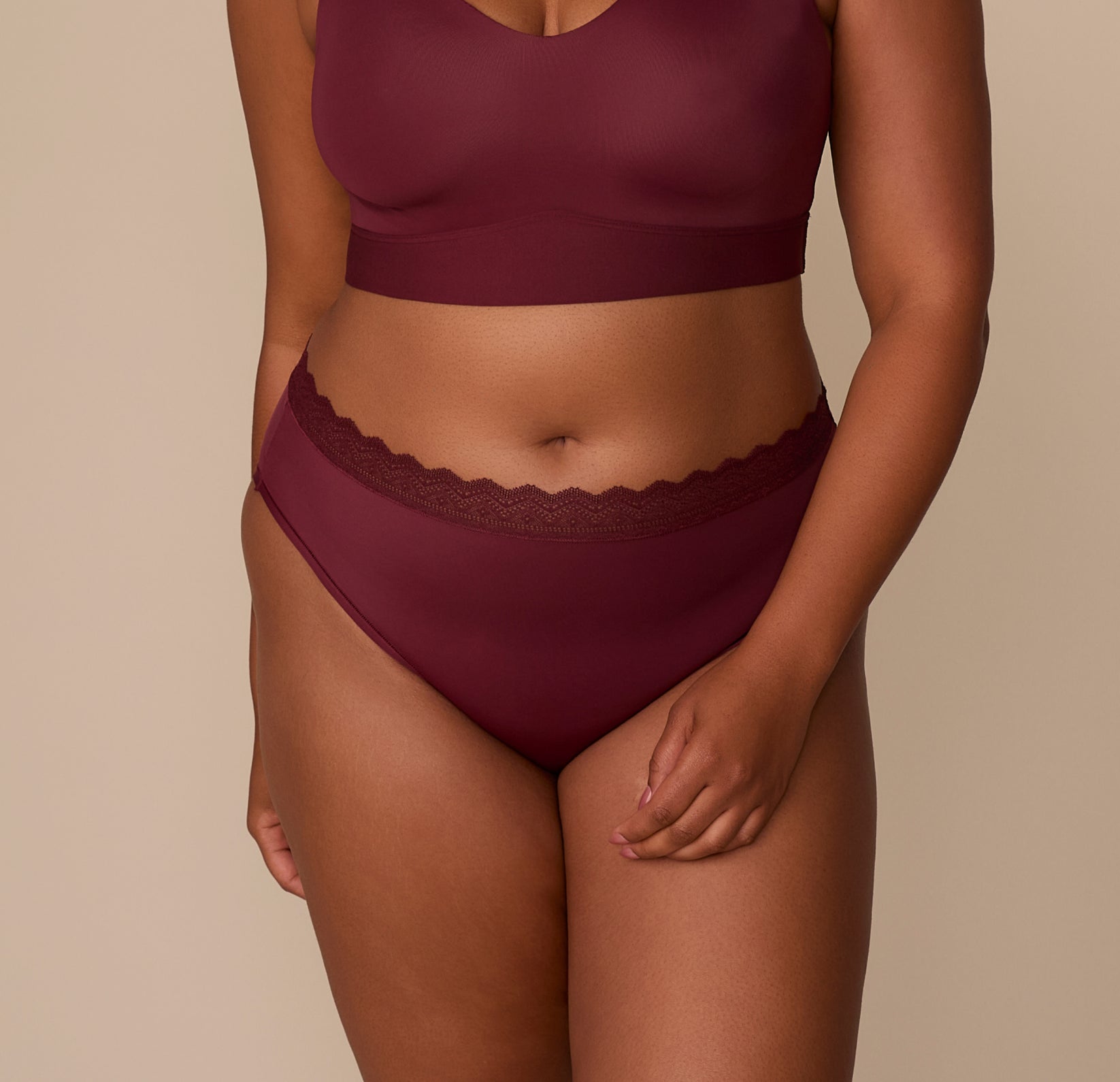 Zarria wears the Bliss Lace Highwaist Brief in Bordeaux. The front view shows the smooth, high-rise silhouette and lace-trimmed waistband designed to hug comfortably without digging in. Sizing: Zarria wears size Xl